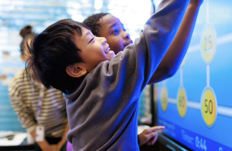 two students smiling and playing with a whiteboard