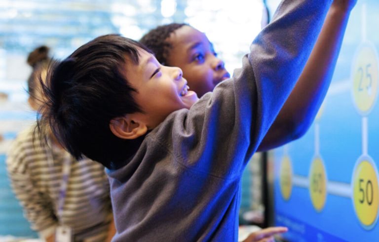 two students smiling and playing with a whiteboard