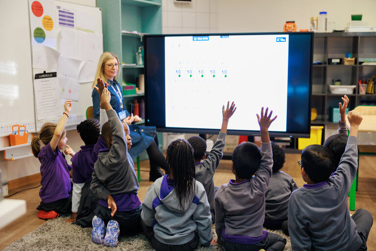 students raise their hands in front of the whiteboard 