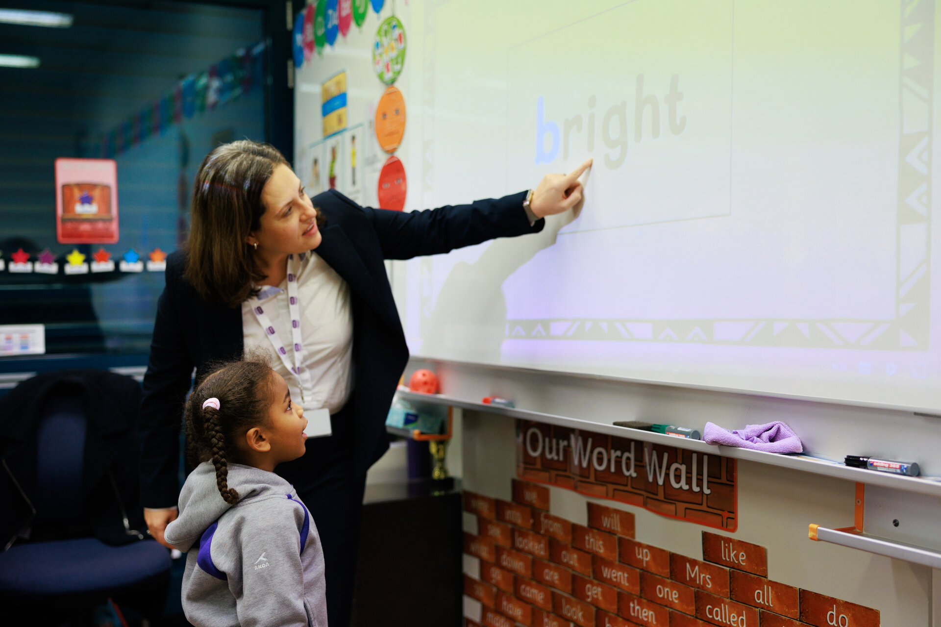 teacher pointing a word on the white board to a student 