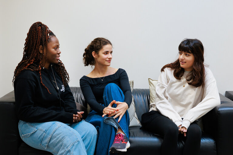 three students smiling on a couch