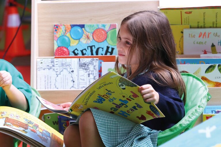 Child smiling while reading a book