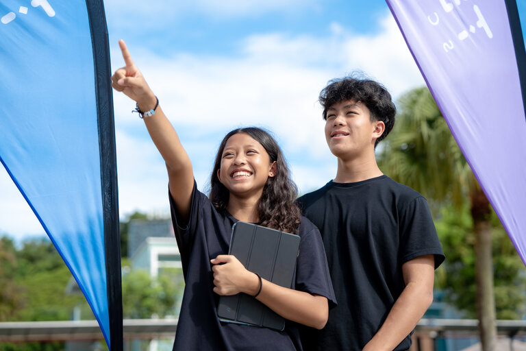 Teenagers smiling and pointing at the sky